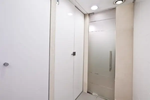 דלתות תאים לבנות ודלת זכוכית חלבית במבואת השירותים