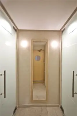 מסדרון צר עם קירות בגוון אבן בהיר ודלתות זכוכית