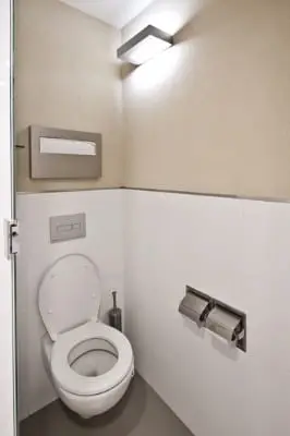 תא שירותים עם אסלה תלויה, חיפוי לבן וחיפוי קיר בגוון חול