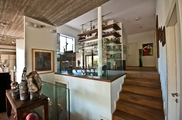 חלל כניסה עם מדרגות עץ, מעקה זכוכית ומדפים פתוחים